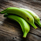 Three green plantains on wooden table